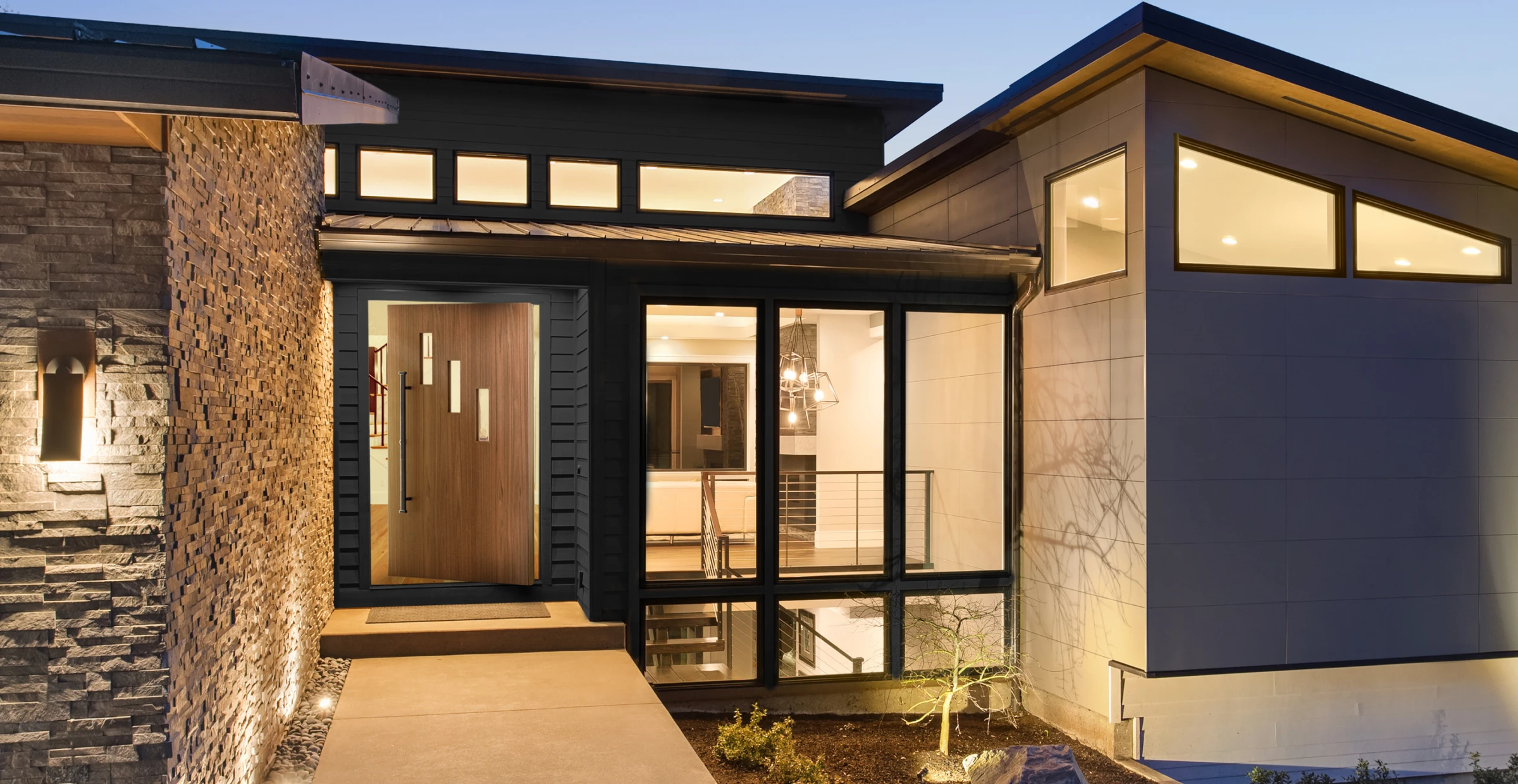 Modern multi-level house with stone and panel siding, pivot front door with glass panels